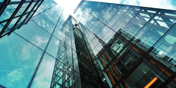 A striking view of a modern glass skyscraper reflecting the sky and clouds.